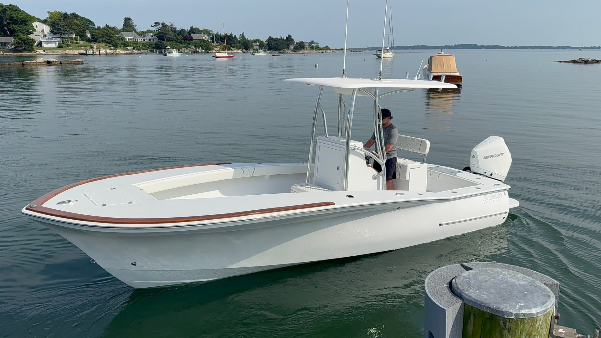 White 23' Stoner center console with teak trim, freshly detailed and idling in a harbor